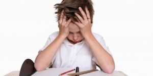 Niño con la cabeza apoyada en las manos frente a un cuaderno en blanco